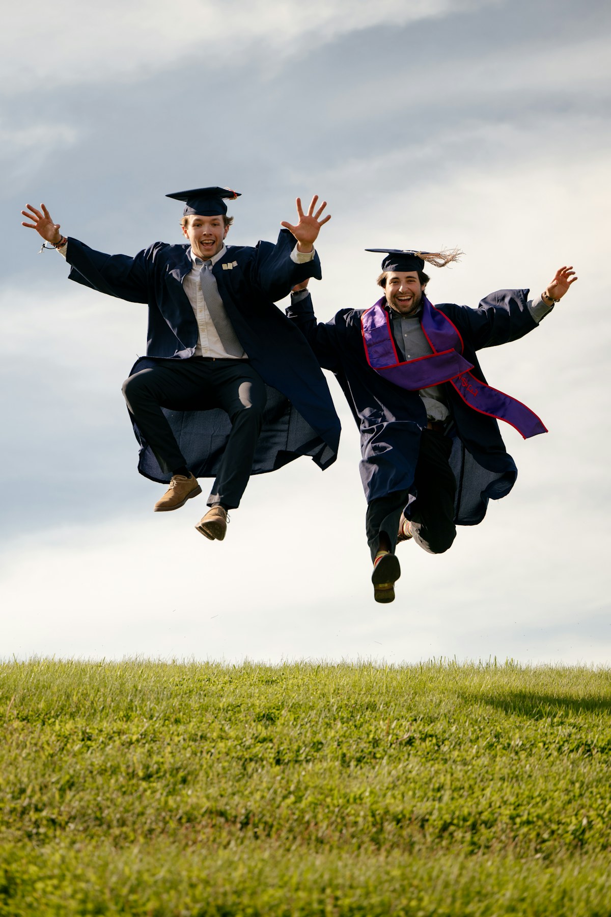 Two graduates leaping with joy, throwing their caps into an open sky